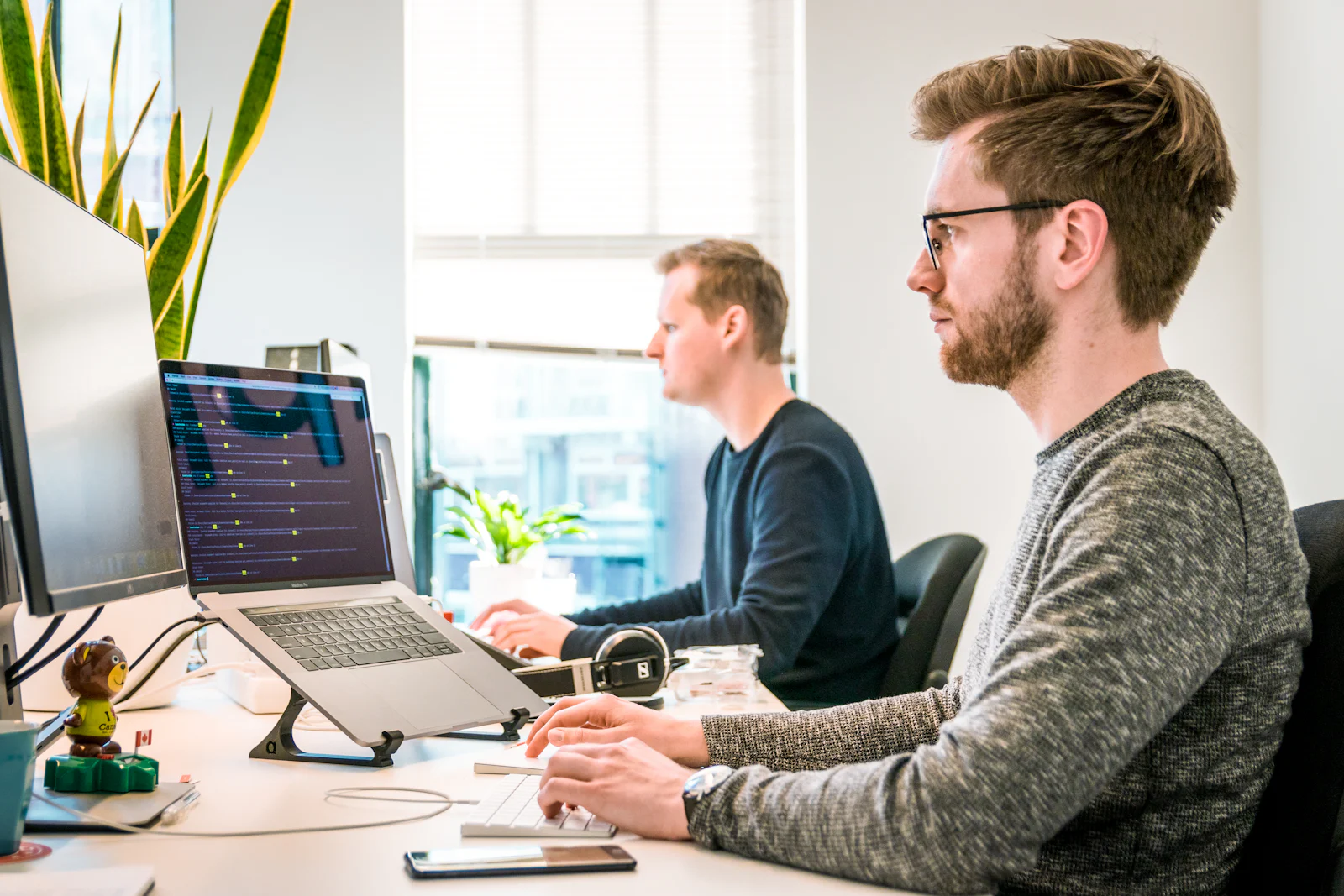Two engineers working at desks with laptops and external monitors