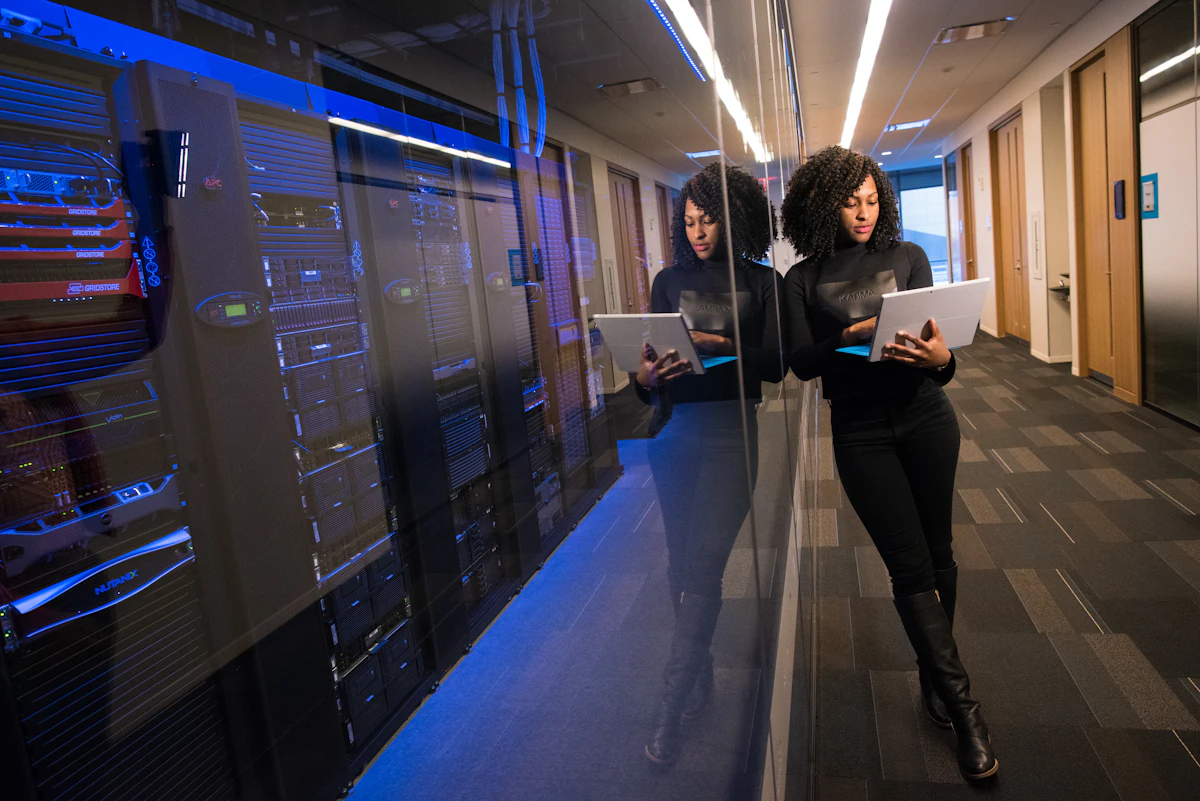 Engineer reviewing a laptop inside a blue-lit data center corridor