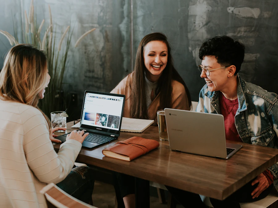 Three colleagues laughing while working together at a table