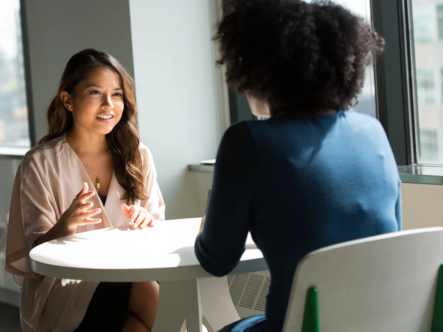 Two colleagues in conversation at a small table by a window